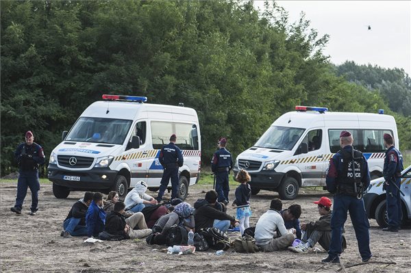 Rendőrök őrzik a megrongált műszaki határzáron átjutott illegális bevándorlókat a röszkei átkelő közelében MTI Fotó: Máthé Zoltán